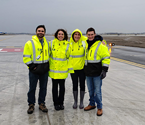 four employees standing on airport runway
