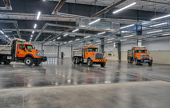 Three dump trucks inside Madison County Highway Facility