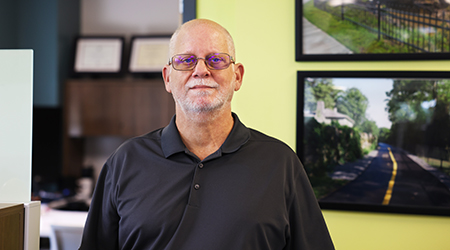 Jason McCray standing in front of FDOT transportation project pictures